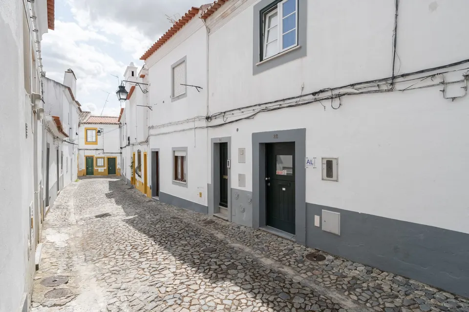 Rua calcetada com casas caiadas de branco e barras cinzentas no centro histórico de Évora