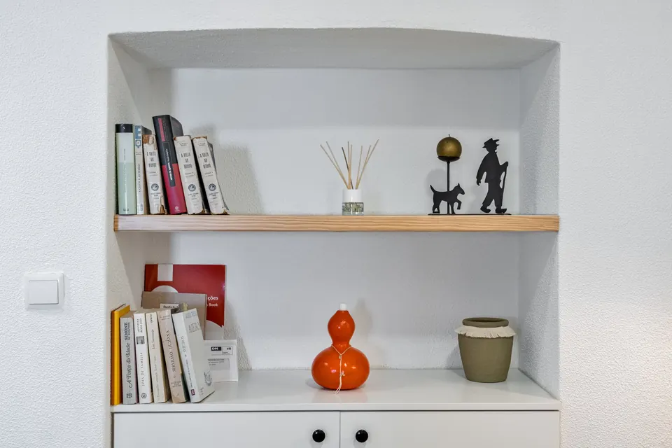 Nicho na parede com livros, difusor e jarra laranja