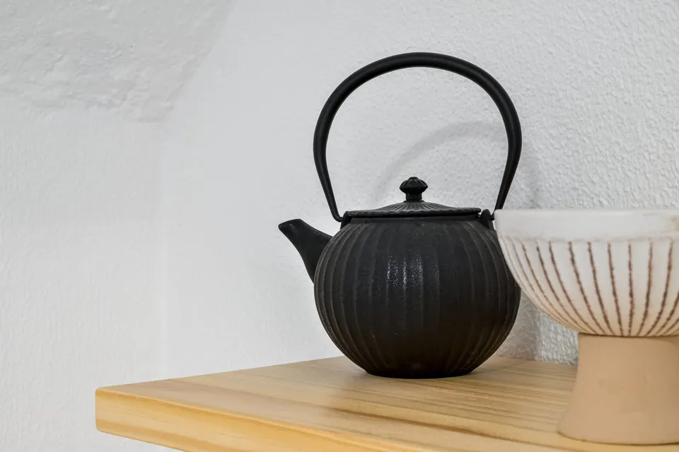 Bule de ferro preto e taça de cerâmica sobre madeira