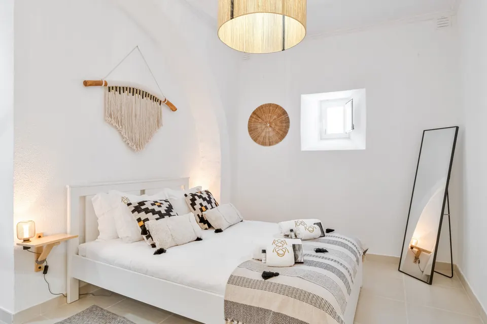 Quarto com cama de casal, macramé na parede e espelho de pé