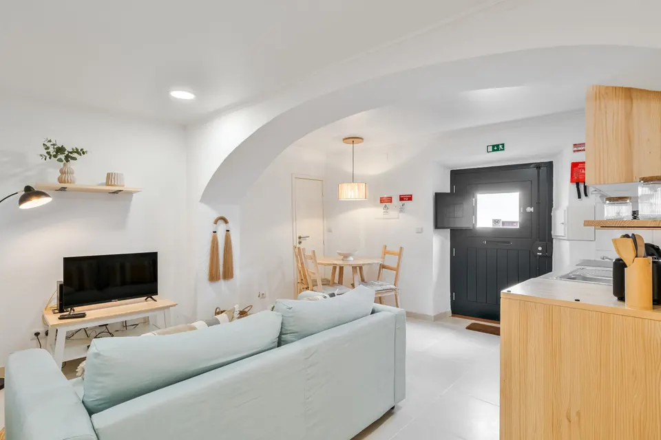Sala aberta para a cozinha, com arco e porta de entrada privada