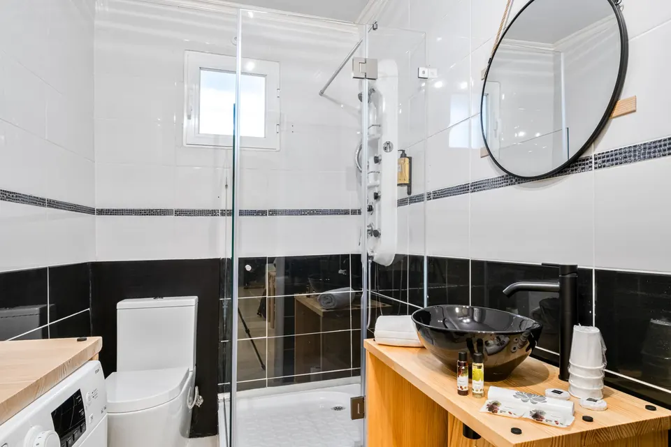 Casa de banho moderna com duche em vidro e lavatório sobre bancada de madeira